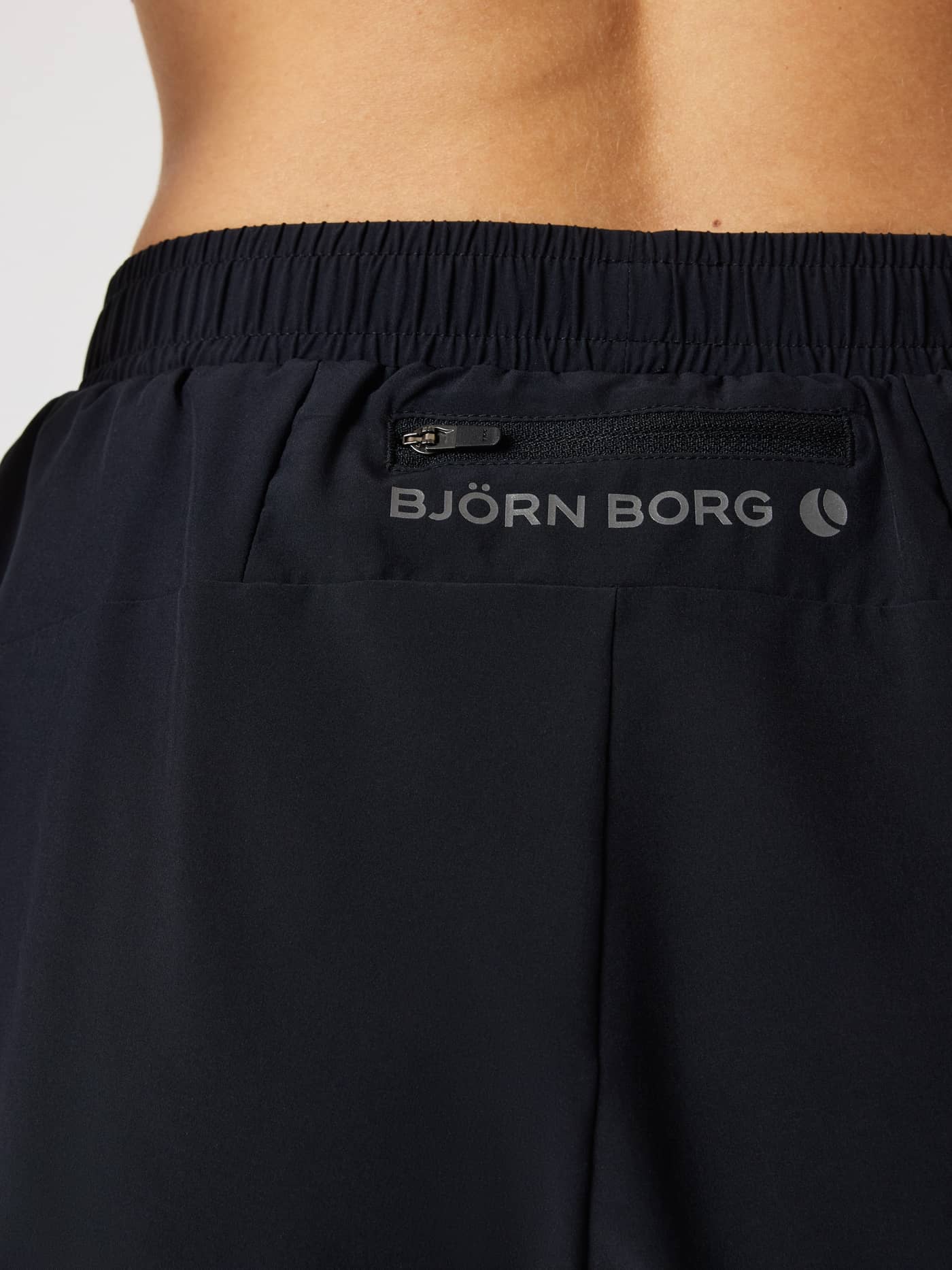 Back view of women's running Borg Performance 2 In 1 Shorts in Black Beauty (Black) with a zip pocket and reflective logo. - Image 4