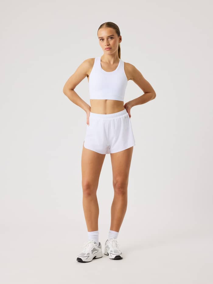 Full-body front view of a woman wearing the Borg Performance 2 In 1 Shorts in Brilliant White (White) for running. - Image 3