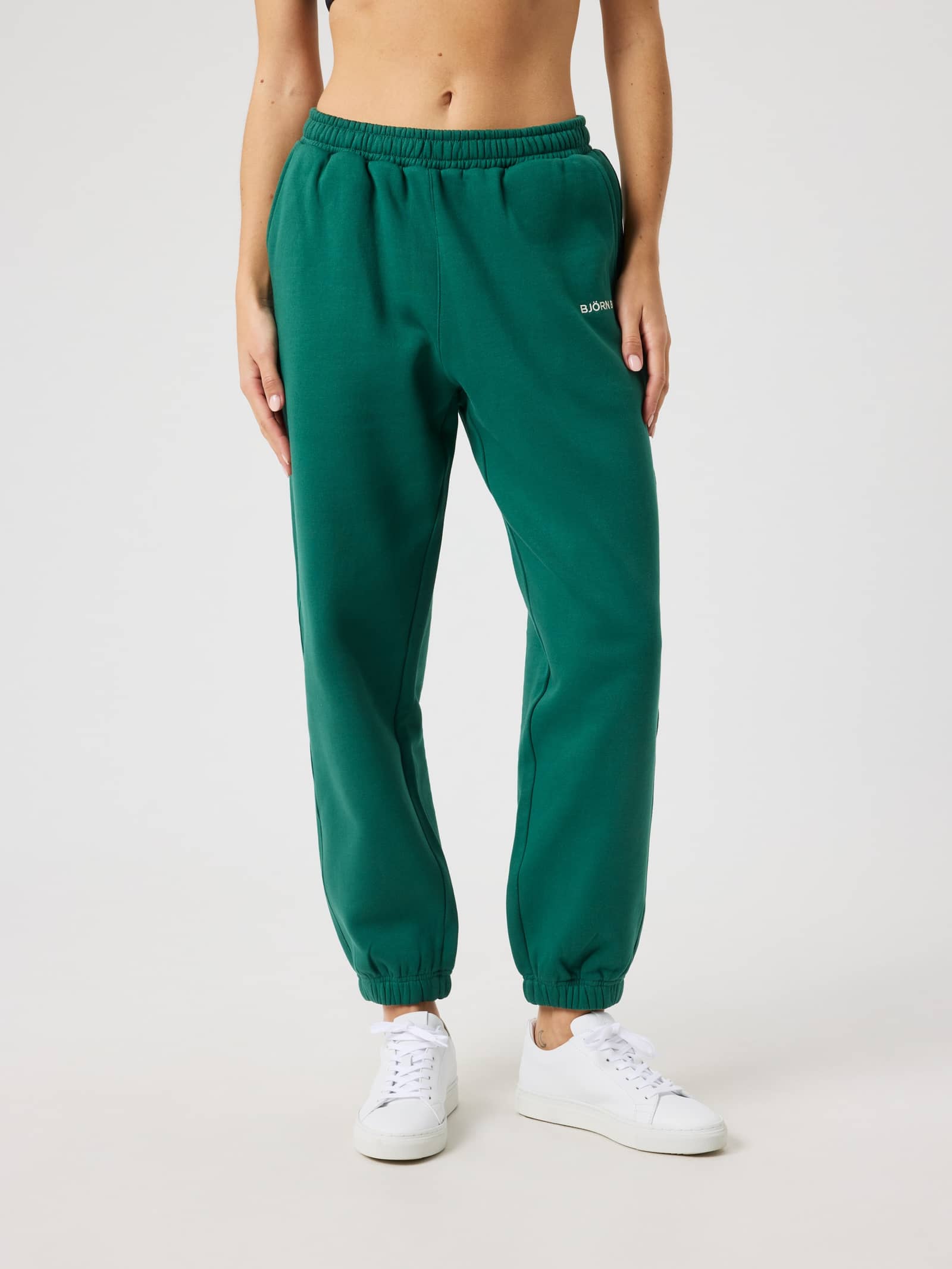 Modell framifrån i Borg Sweatpants i Posy Green (Grön) med regular fit och vit logotyp för tennis. - Image 1
