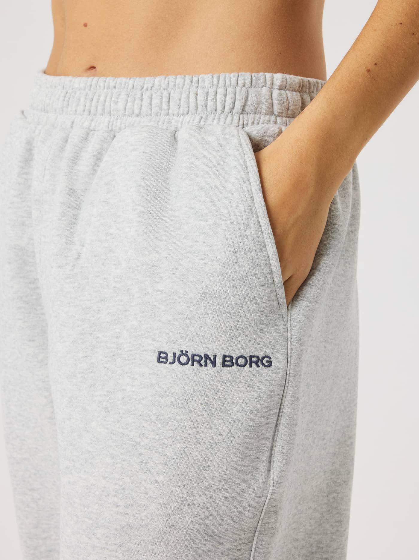 Gros plan latéral du Borg Sweatpants pour femme en coton Ultra Light Grey Melange (Gris) avec logo bleu marine et poche. - Image 5