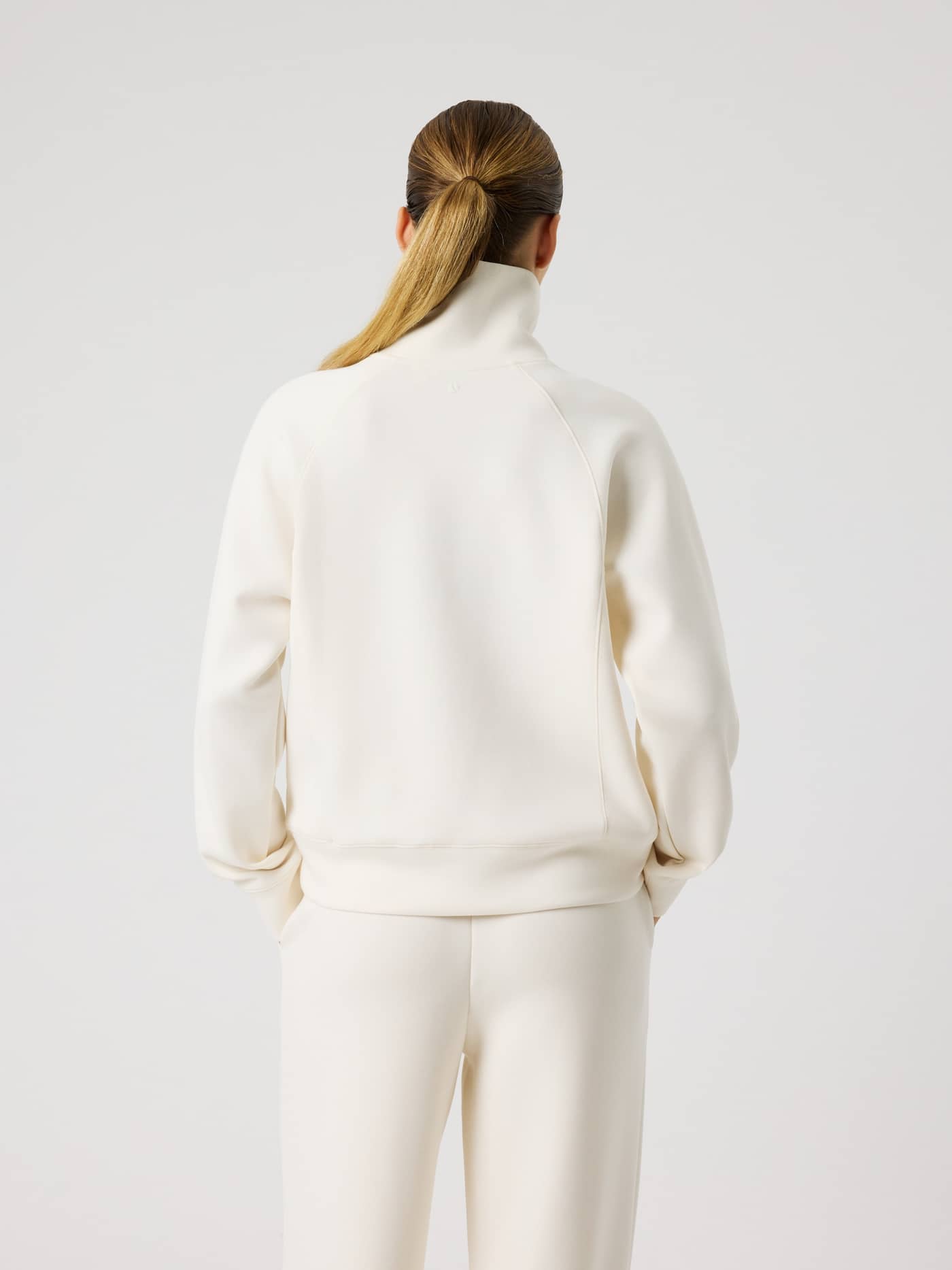 Back view of a woman wearing the Studio Soft Halfzip Sweatshirt in Tofu (White), featuring a soft feel and stylish loose fit. - Image 5