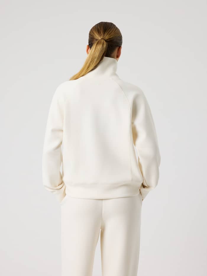 Back view of a woman wearing the Studio Soft Halfzip Sweatshirt in Tofu (White), featuring a soft feel and stylish loose fit.