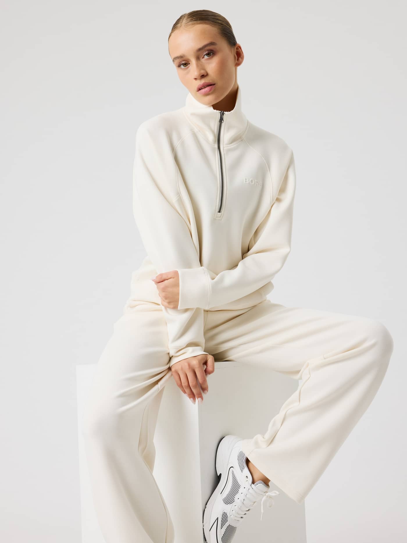 Front view of a model in the Studio Soft Halfzip Sweatshirt in Tofu (White) with a stylish high collar and loose fit. - Image 1