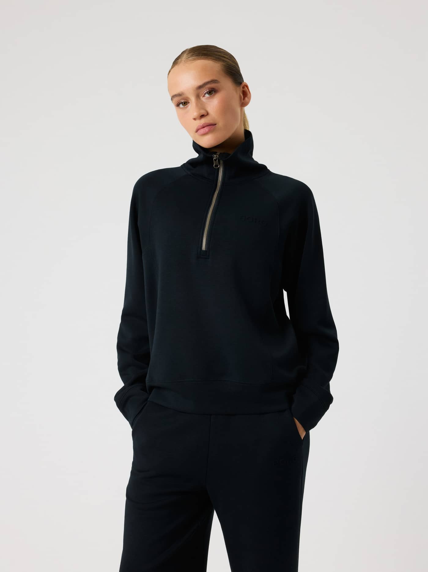 Front view of a woman in the Studio Soft Halfzip Sweatshirt in Black Beauty (Black) featuring a black logo and loose fit. - Image 1