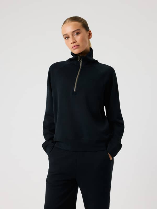 Front view of a woman in the Studio Soft Halfzip Sweatshirt in Black Beauty (Black) featuring a black logo and loose fit.