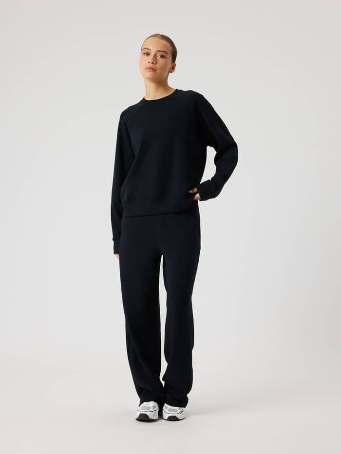Ganzkörper-Vorderansicht einer Frau im Studio Soft Sweatshirt in Black Beauty (Schwarz) mit entspannter Modal-Passform. - Image 3