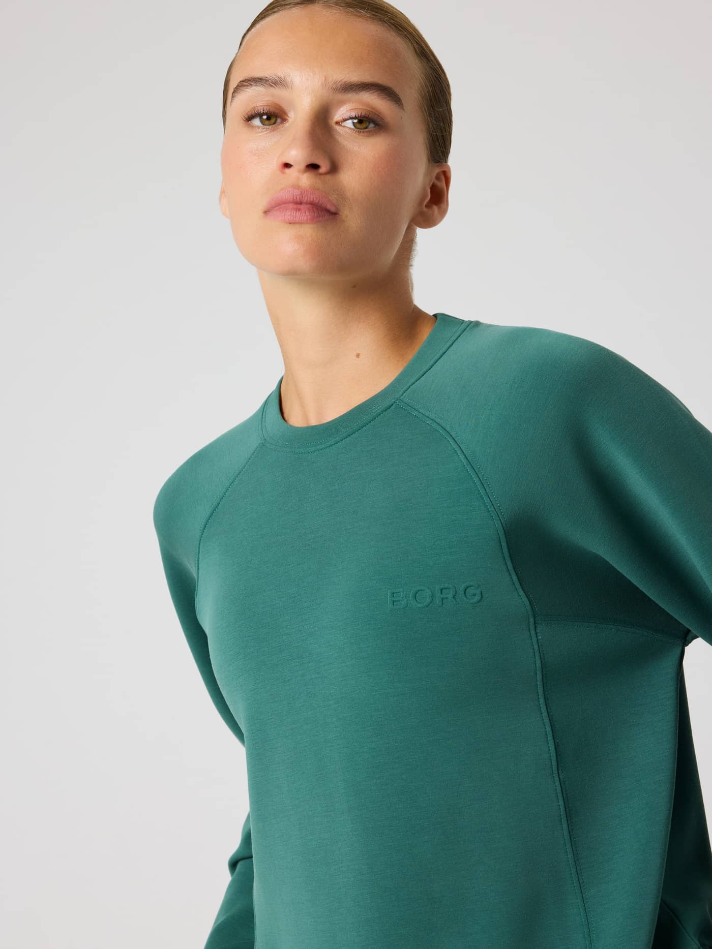 Front close-up of a model in the Studio Soft Sweatshirt in Mallard Green (Green), featuring a tonal BORG chest logo. - Image 4