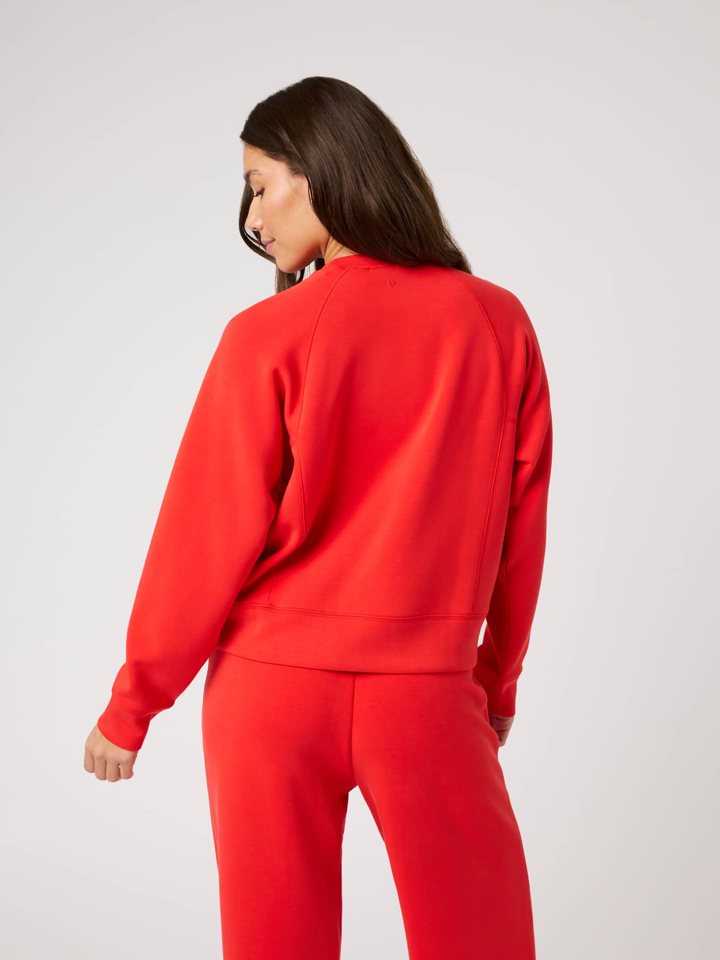 Back view of a model in the Björn Borg Studio Soft Sweatshirt in Flame Scarlet (Red) with raglan sleeves and a tennis detail. - Image 2