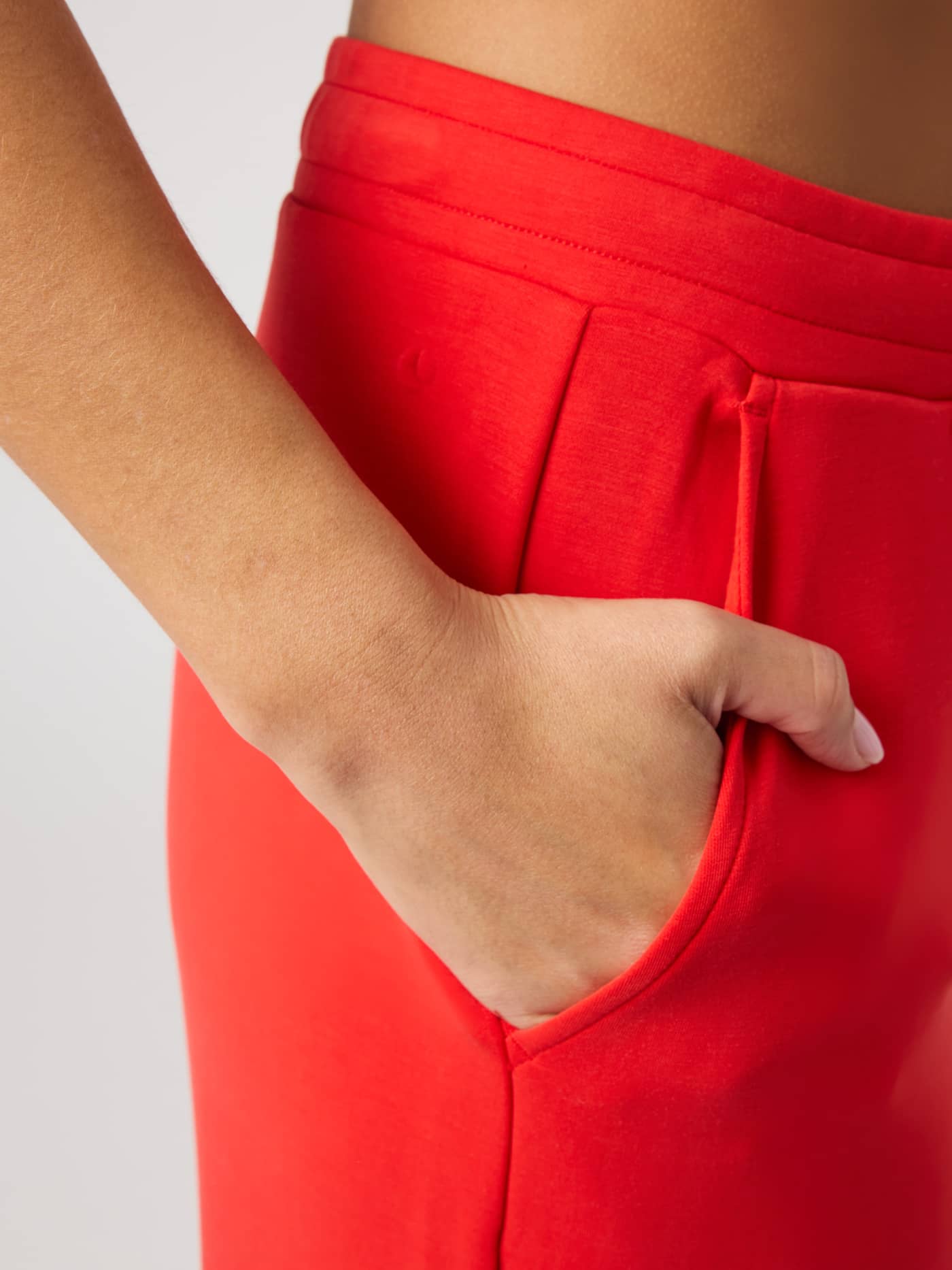 Close-up of the Studio Soft Sweatpants in Flame Scarlet (Red) highlighting the side pocket and soft, flexible fabric. - Image 5