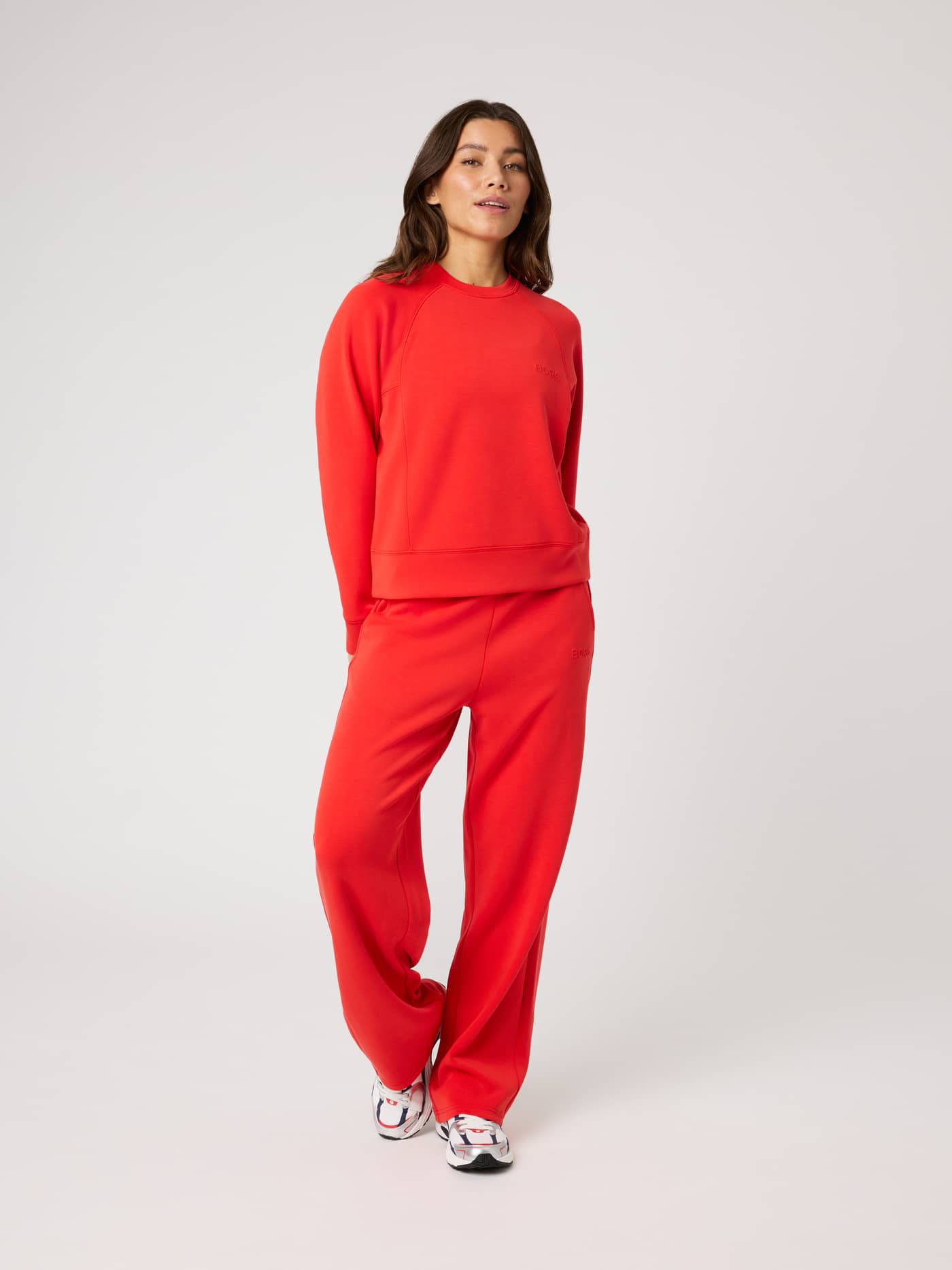 Front view of a model in Studio Soft Sweatpants in Flame Scarlet (Red) with a red logo for a relaxed tennis look. - Image 7