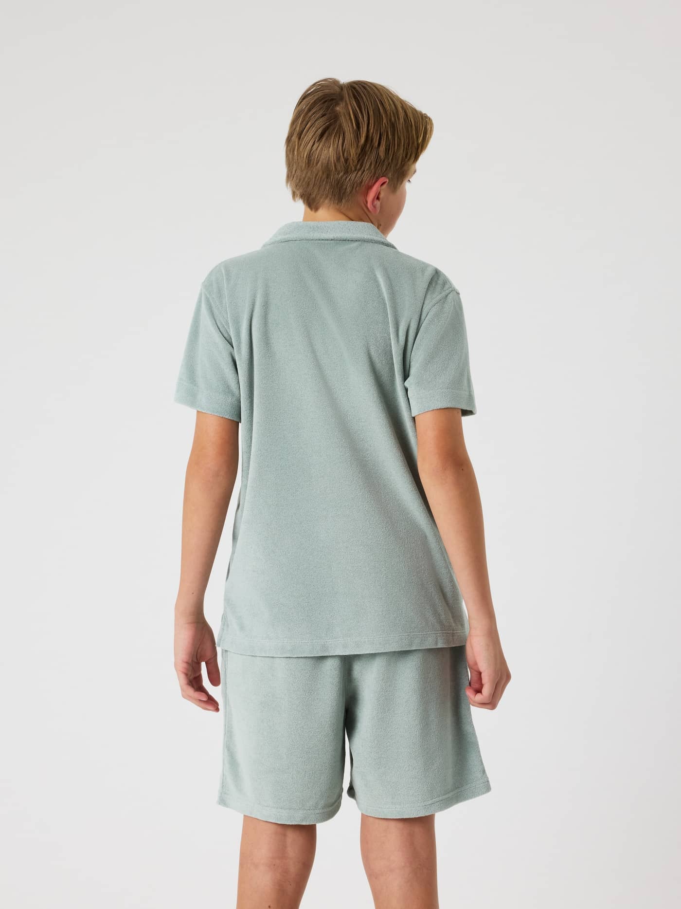 Back view of a kids' model in the regular fit Borg Toweling Pool Shirt in Slate Gray (Green), made of soft toweling. - Image 2