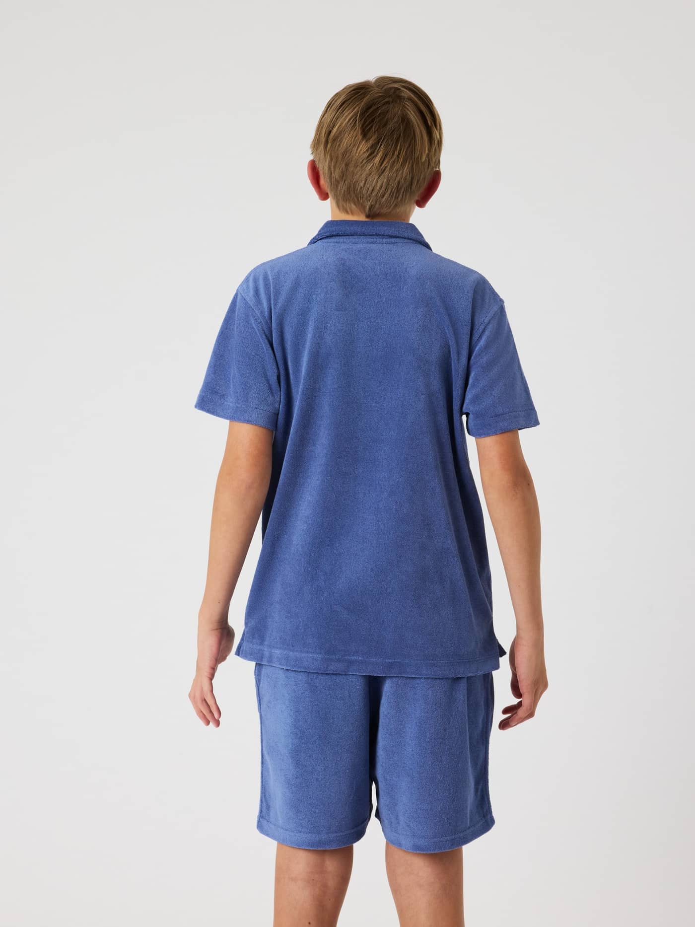 Back view of a kid wearing the Borg Toweling Pool Shirt in Coastal Fjord (Blue), crafted from soft toweling fabric. - Image 2