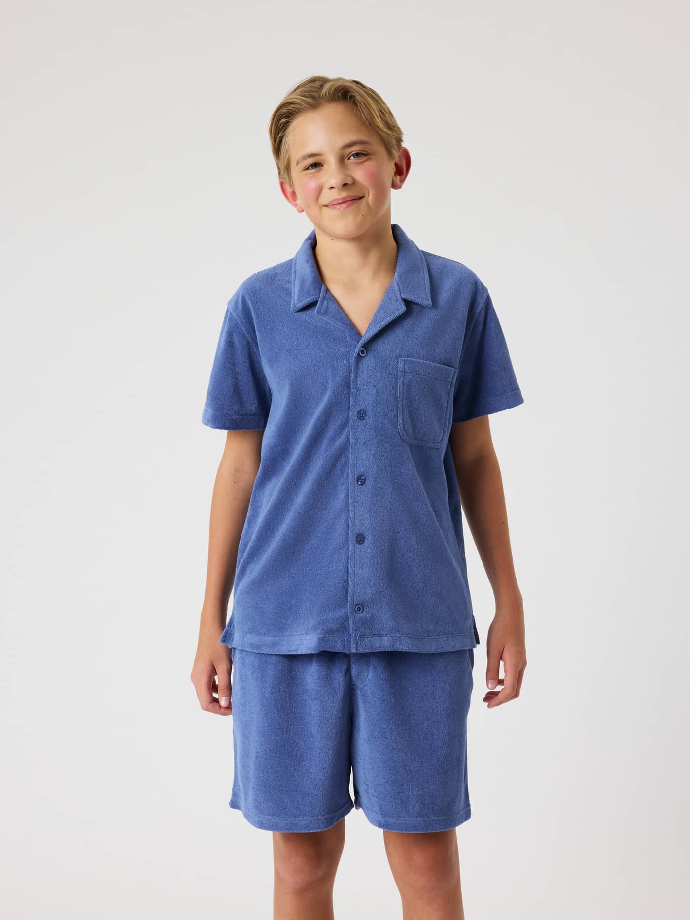 Front view of a kid wearing the Björn Borg Toweling Pool Shirt in Coastal Fjord (Blue), a soft toweling shirt for kids. - Image 1