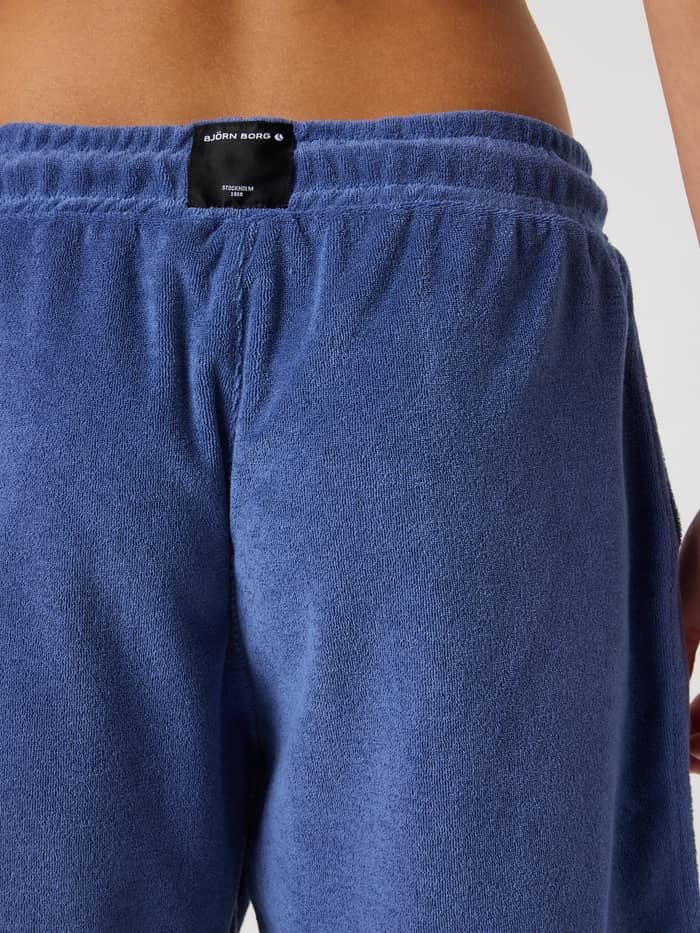 Borg Toweling Pool Shorts til kids i Coastal Fjord (Blå) i nærbillede bagfra med et sort vævet logomærke. - Image 4
