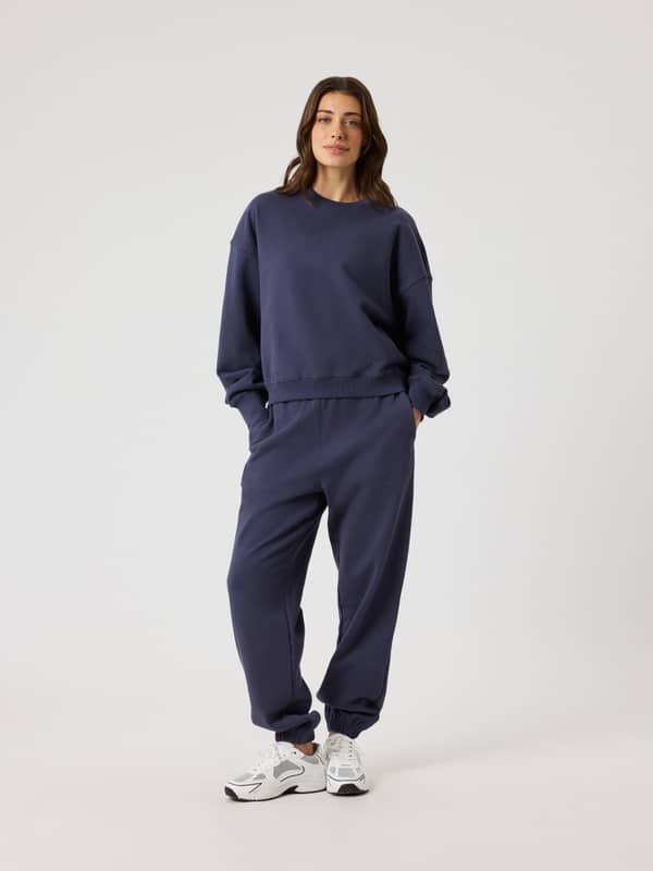 Full-body front view of a woman in Odyssey Gray (Navy) Studio Oversized Sweatshirt, with a stylish fit and tonal BORG logo.