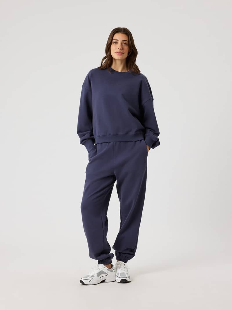 Full-body front view of a woman in Odyssey Gray (Navy) Studio Oversized Sweatshirt, with a stylish fit and tonal BORG logo.