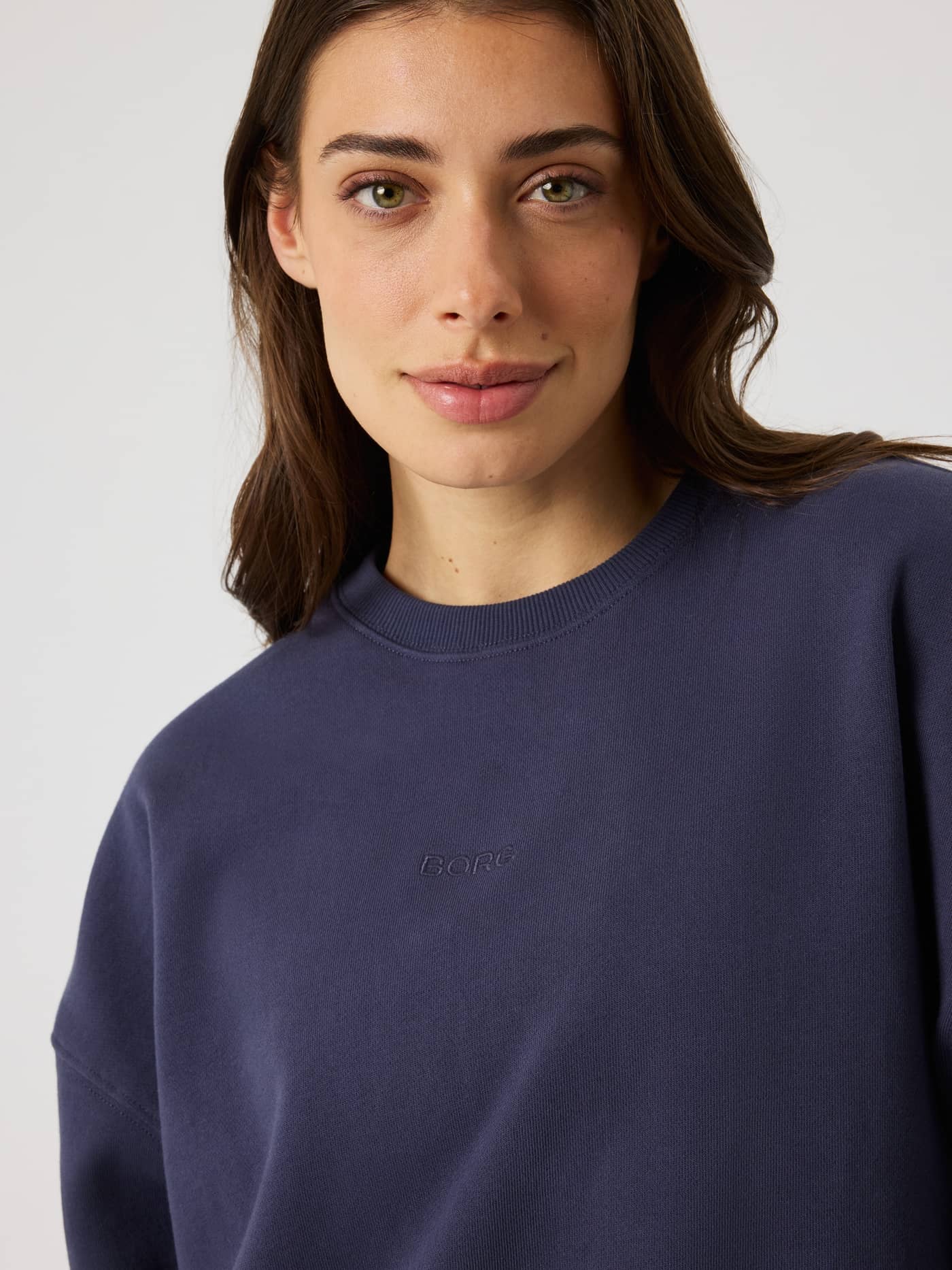 Nærbilde av kvinne i Studio Oversized Sweatshirt i Odyssey Gray (marineblå) med ton-i-ton BORG-logo. - Image 5