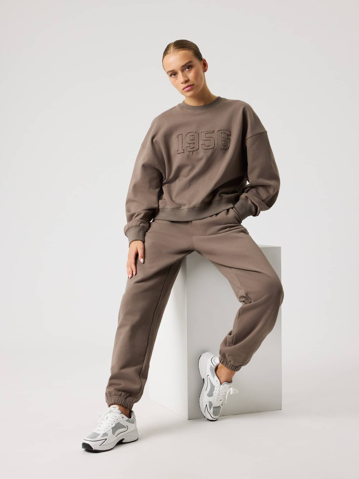Full-body view of a woman in the Falcon (Brown) Studio Oversized Sweatshirt, featuring a relaxed fit and tonal 1956 logo. - Image 5