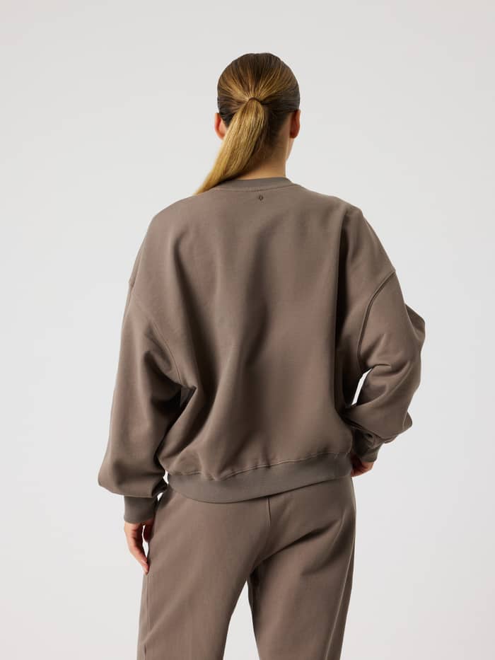 Rückansicht eines Models im Studio Oversized Sweatshirt in Falcon (Braun) für Damen mit lockerer Oversized-Passform. - Image 3