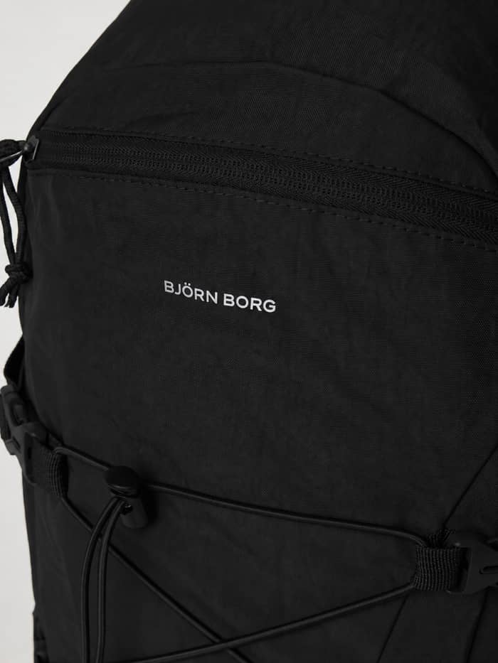 Close-up of the Borg Explorer Backpack 28L in Black Beauty (Black) featuring a front zipper pocket and white logo. - Image 4