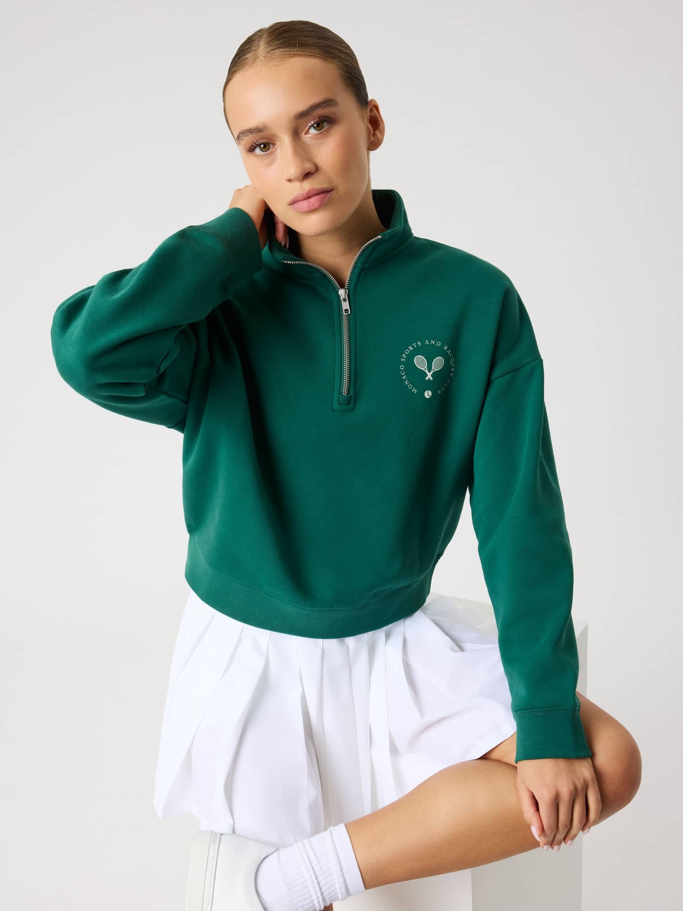 Front view of a woman wearing the Borg Halfzip Sweatshirt in Posy Green (Green) with a light green tennis logo. - Image 1