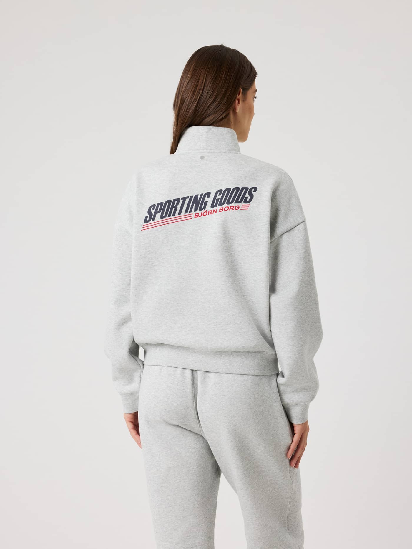 Back view of a model wearing the Borg Halfzip Sweatshirt in Ultra Light Grey Melange (Grey) with a navy and red back logo. - Image 3