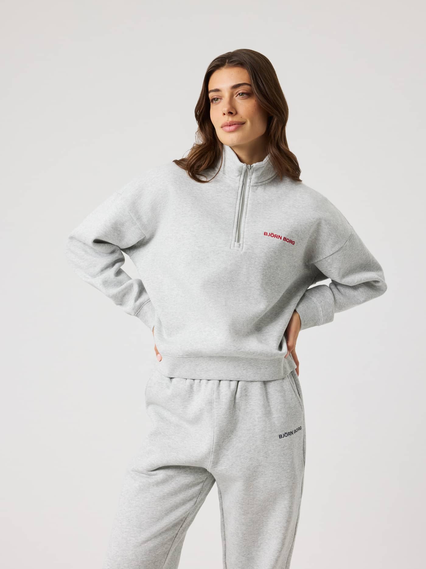 Front view of a woman wearing the cotton-blend Borg Halfzip Sweatshirt in Ultra Light Grey Melange (Grey) with a red logo. - Image 2