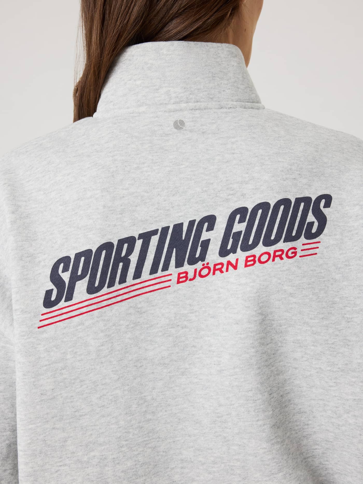 Back view of the soft Ultra Light Grey Melange (Grey) Borg Halfzip Sweatshirt for women with a stylish navy and red logo. - Image 4