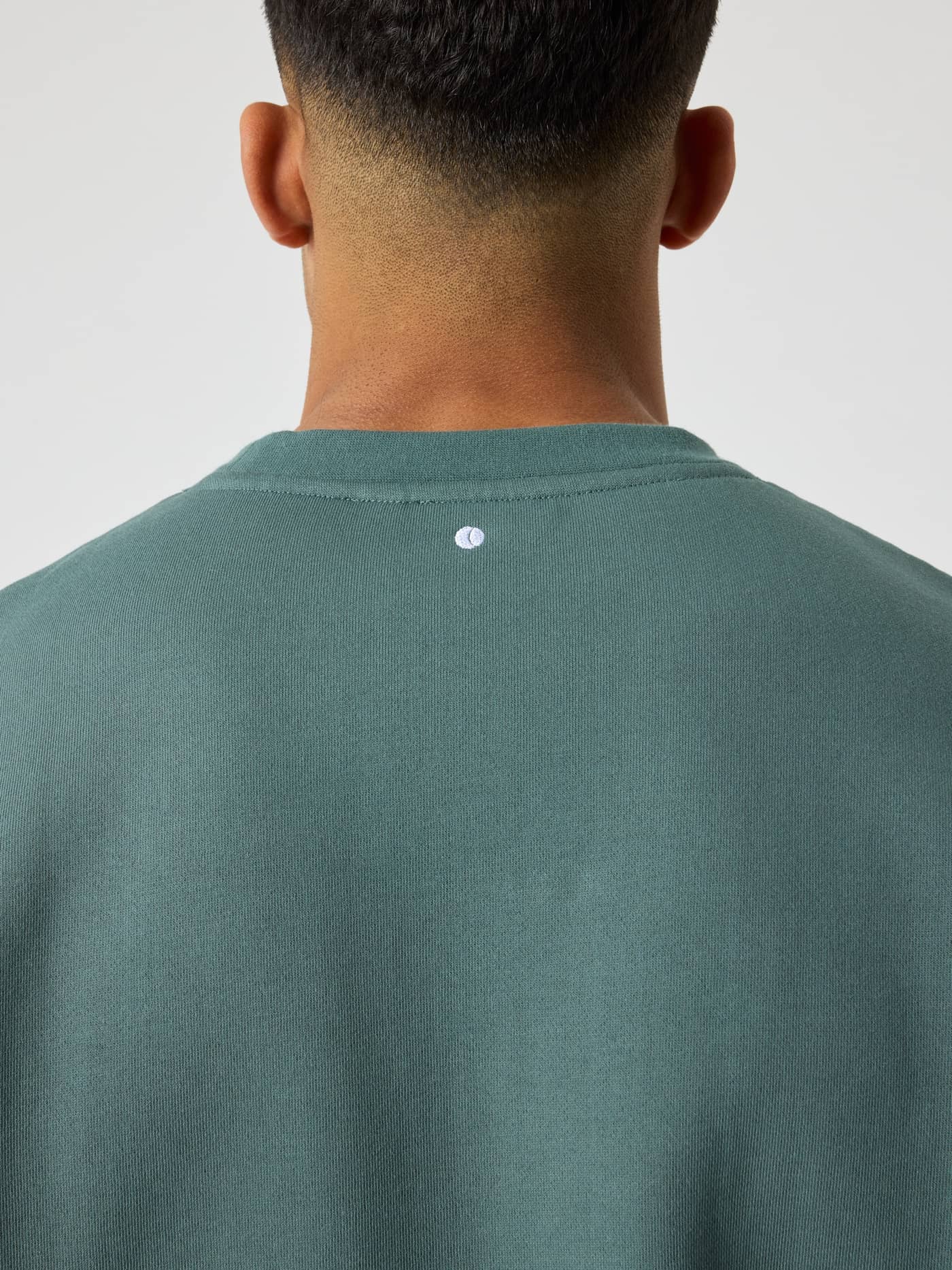 Nahaufnahme des Borg Oversized Logo Sweatshirt in Balsam Green (Grün) mit weißem Tennisball-Detail am Nacken. - Image 5
