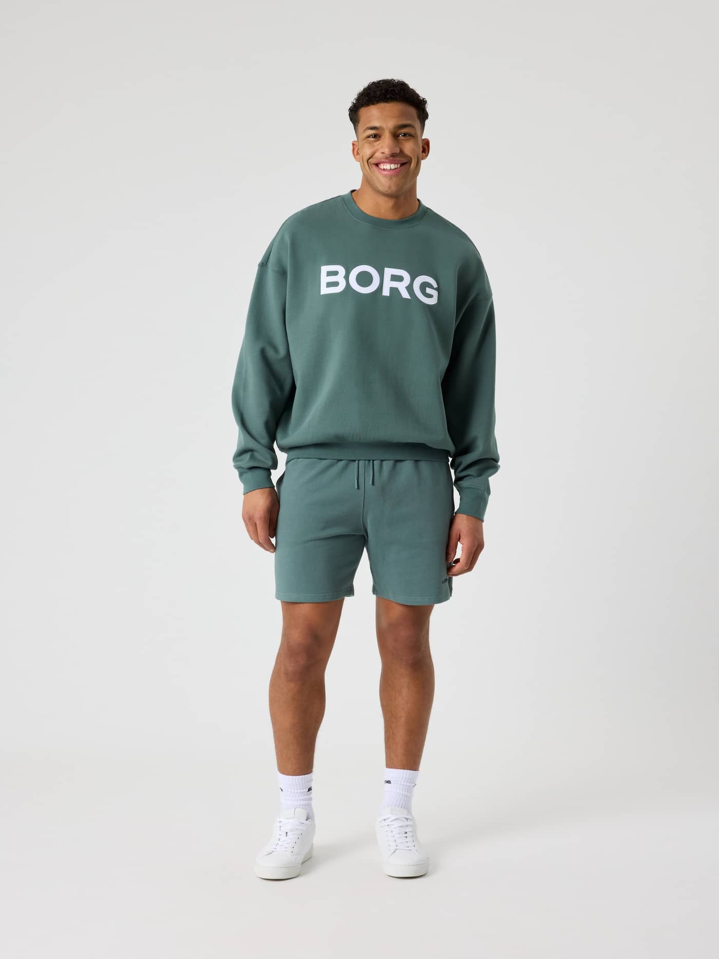 Ganzkörper-Vorderansicht eines Mannes im Borg Oversized Logo Sweatshirt in Balsam Green (Grün) mit weißem Logo. - Image 4