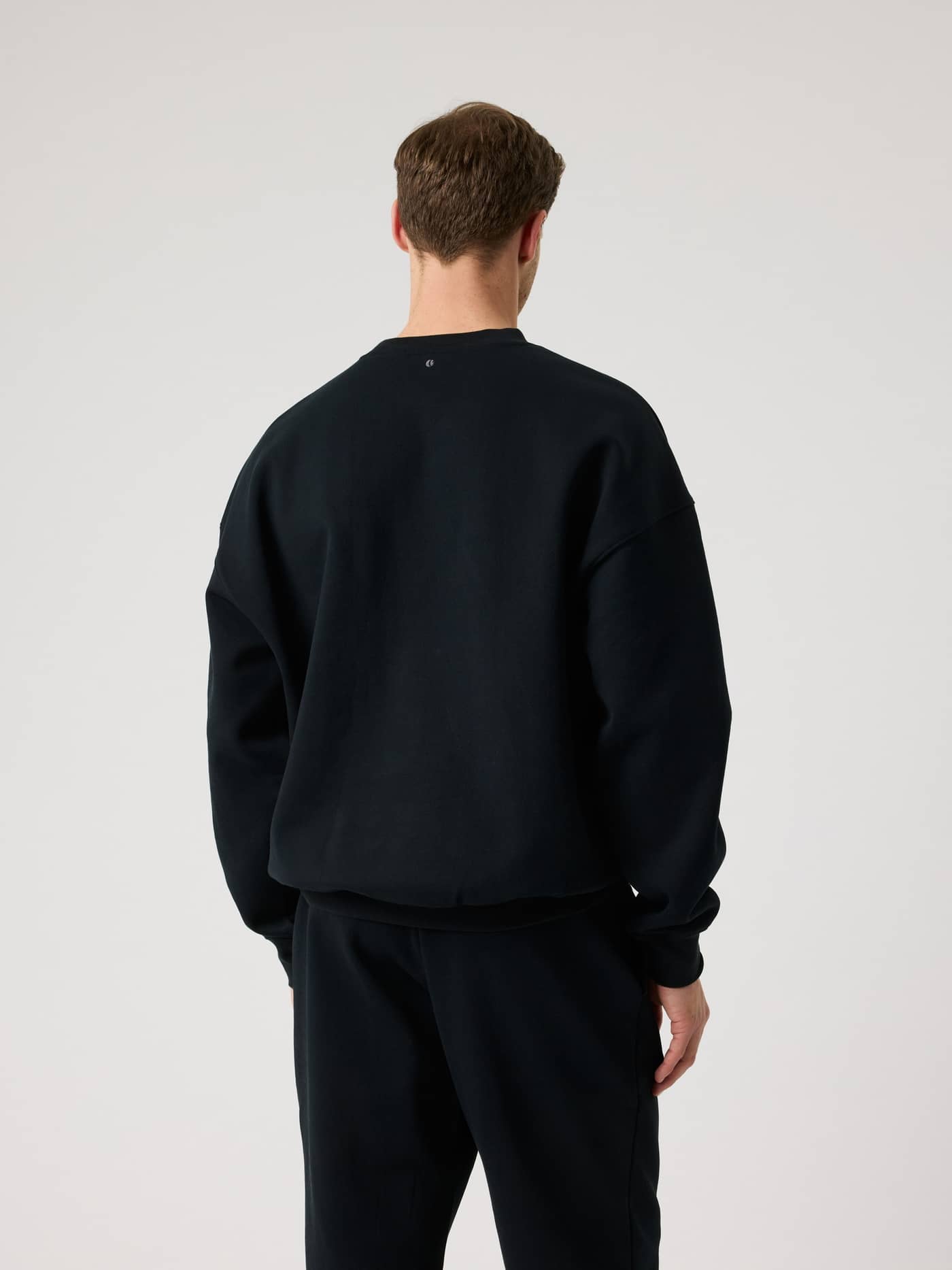 Rückansicht eines Mannes im Borg Oversized Logo Sweatshirt in Black Beauty (Schwarz) mit Tennisball-Print fürs Training. - Image 2