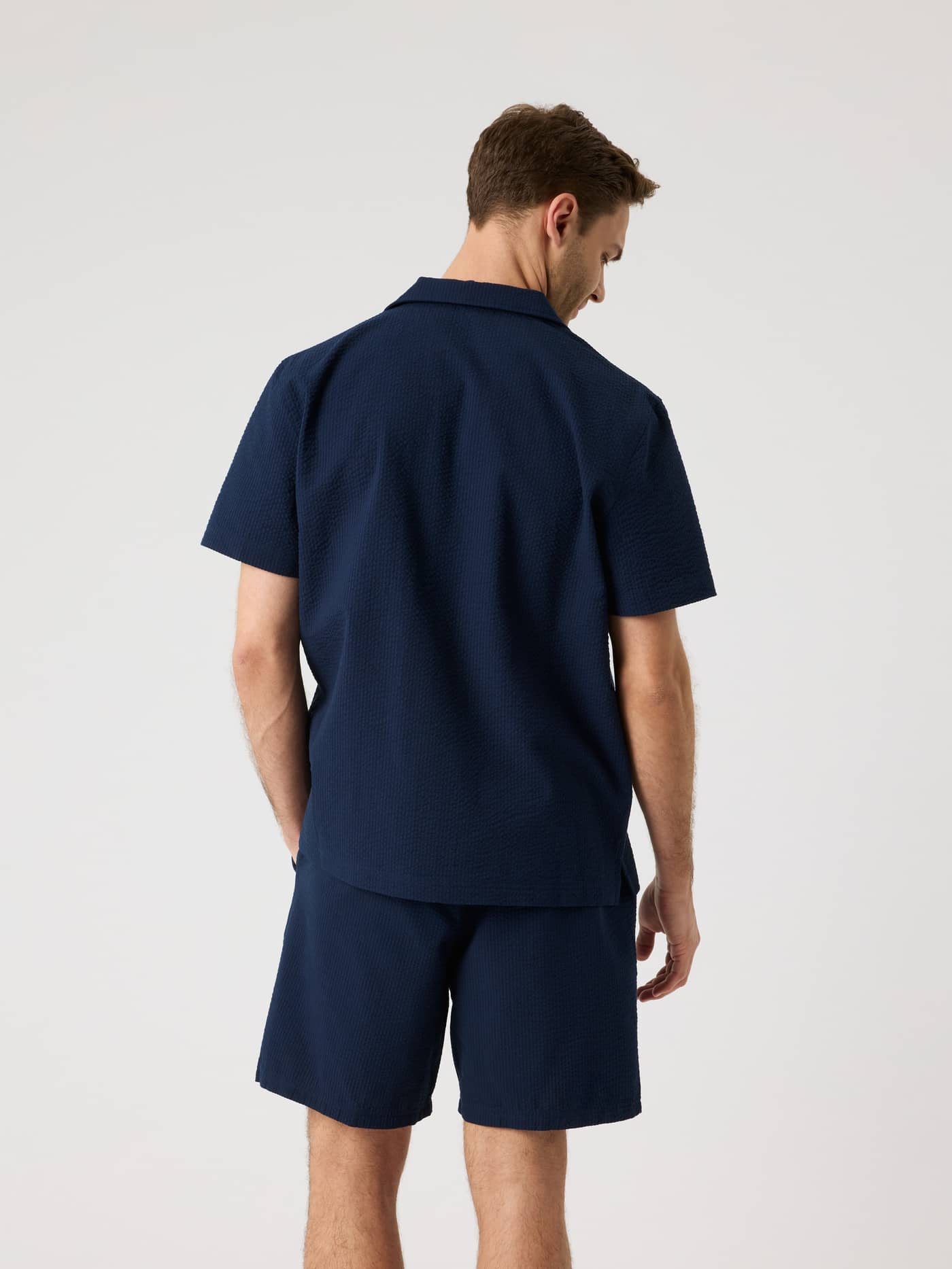 Back view of a man wearing the Borg Seersucker Resort Shirt in Night sky (Navy) in a regular fit with textured fabric. - Image 2