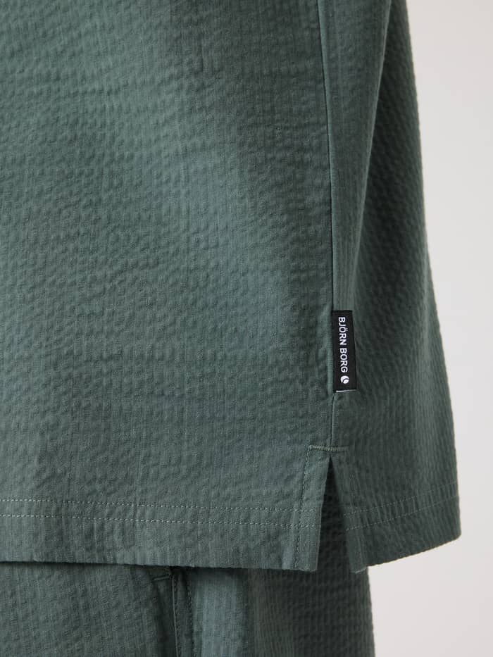 Nahaufnahme des Borg Seersucker Resort Shirt in Balsam Green (Grün) mit weißem Logo-Flaggenlabel und Seitenschlitz. - Image 5