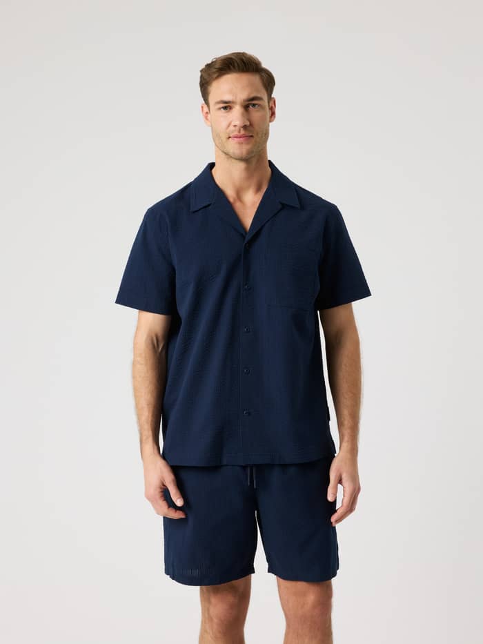 Front view of a model in the Borg Seersucker Resort Shirt in Night sky (Navy) with a functional camp collar and regular fit.