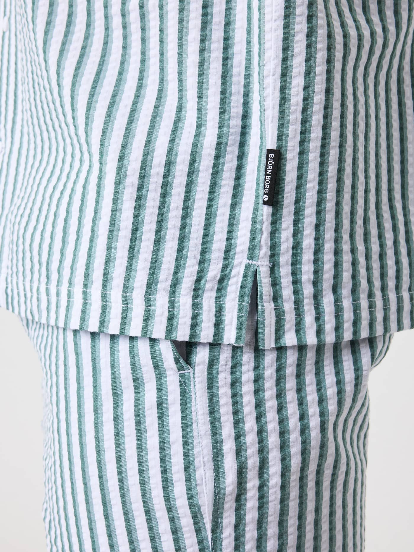 Primer plano de la Borg Seersucker Resort Shirt a rayas en 7 Stripe 1 (Verde y Blanco) con abertura lateral y logo negro. - Image 5