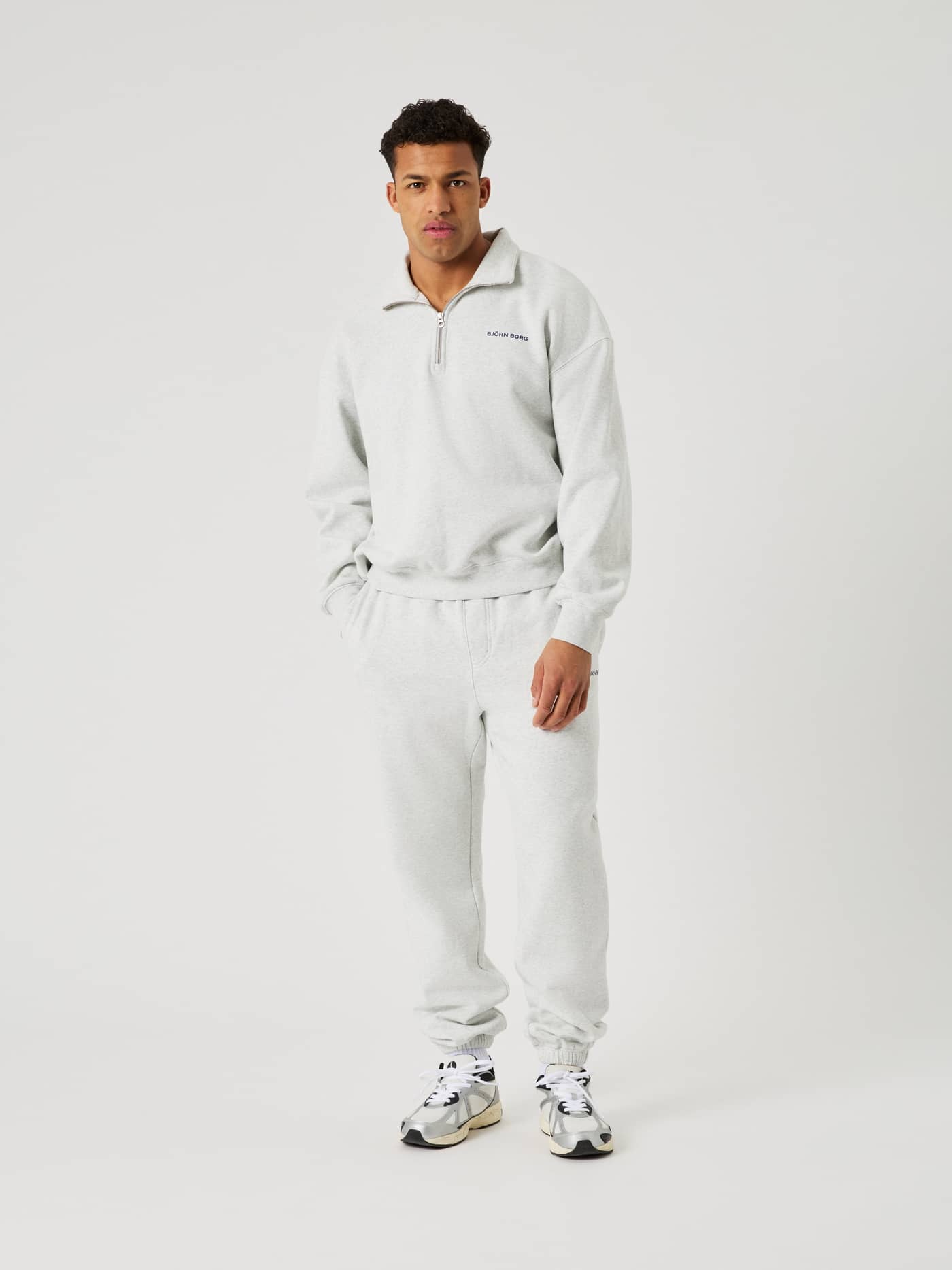 Full-body front view of a man wearing the Borg Oversized Sweatpants in Ultra Light Grey Melange (Grey) with tennis details. - Image 3