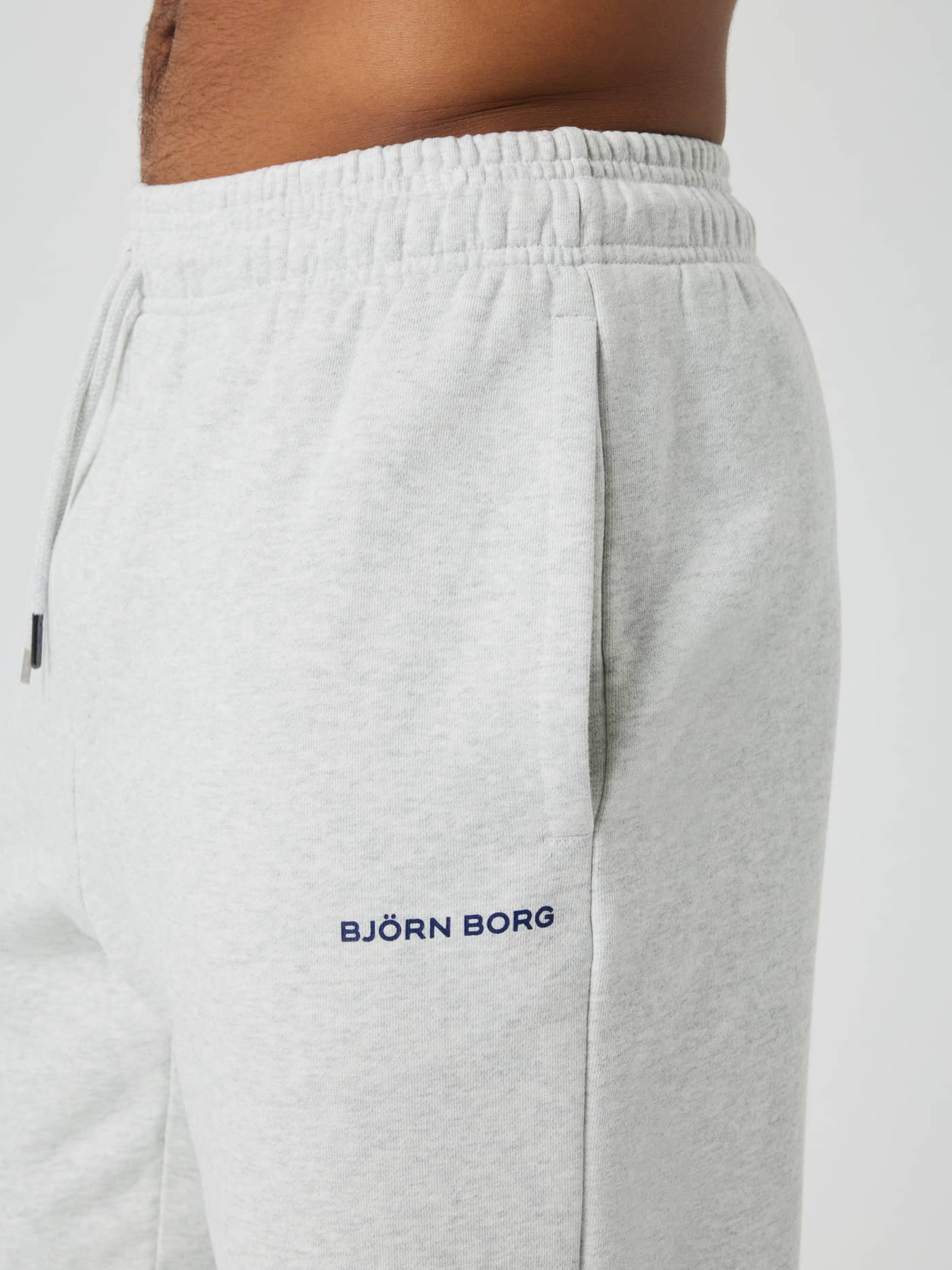 Side view of the Björn Borg Oversized Sweatpants in Ultra Light Grey Melange (Grey) with a side pocket and navy logo. - Image 5