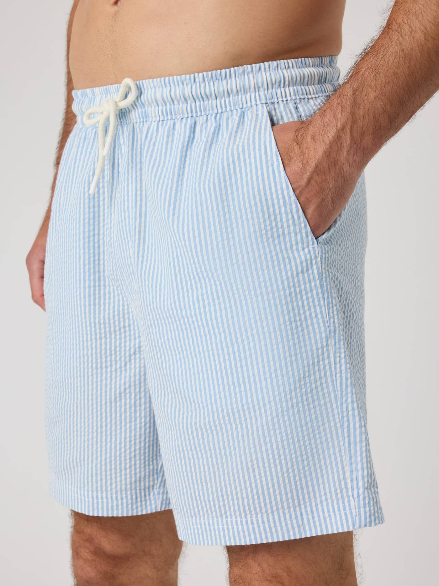 Vista lateral de un hombre con Borg Seersucker Resort Shorts en Shirt Stripe 1 (Azul) de algodón orgánico y ajuste regular. - Image 5