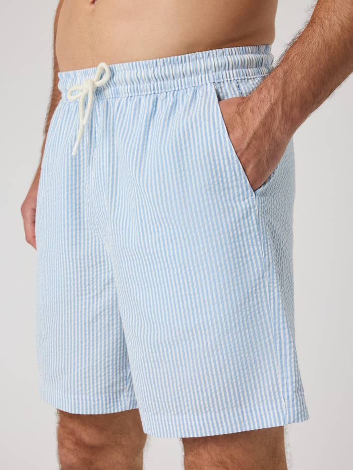 Zijaanzicht van een man in de gestreepte Borg Seersucker Resort Shorts in Shirt Stripe 1 (Blauw) van biologisch katoen. - Image 5