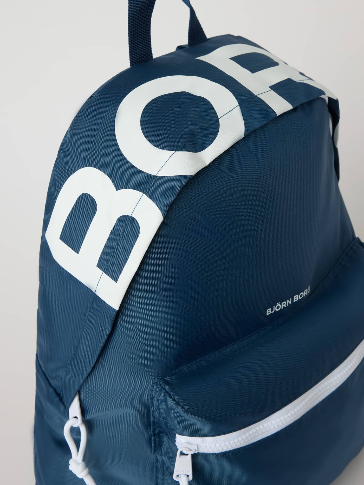 Nahaufnahme des Borg Logo Backpack 27L in Sargasso Sea (Marineblau) mit markantem weißem Logo aus robustem Polyester. - Image 3