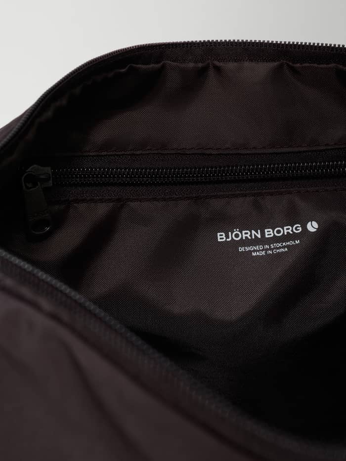 Interieurdetail van de Studio Active Shoulder Bag 20L in Coffee Bean (Bruin) met wit logo en ritsvak voor training. - Image 2