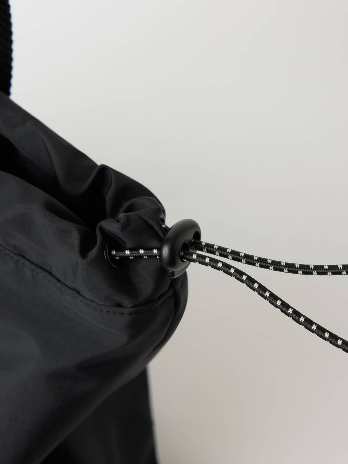 Detailed close-up of the drawstring toggle on the Studio Active Tote 18L in Black Beauty (Black) for training. - Image 4