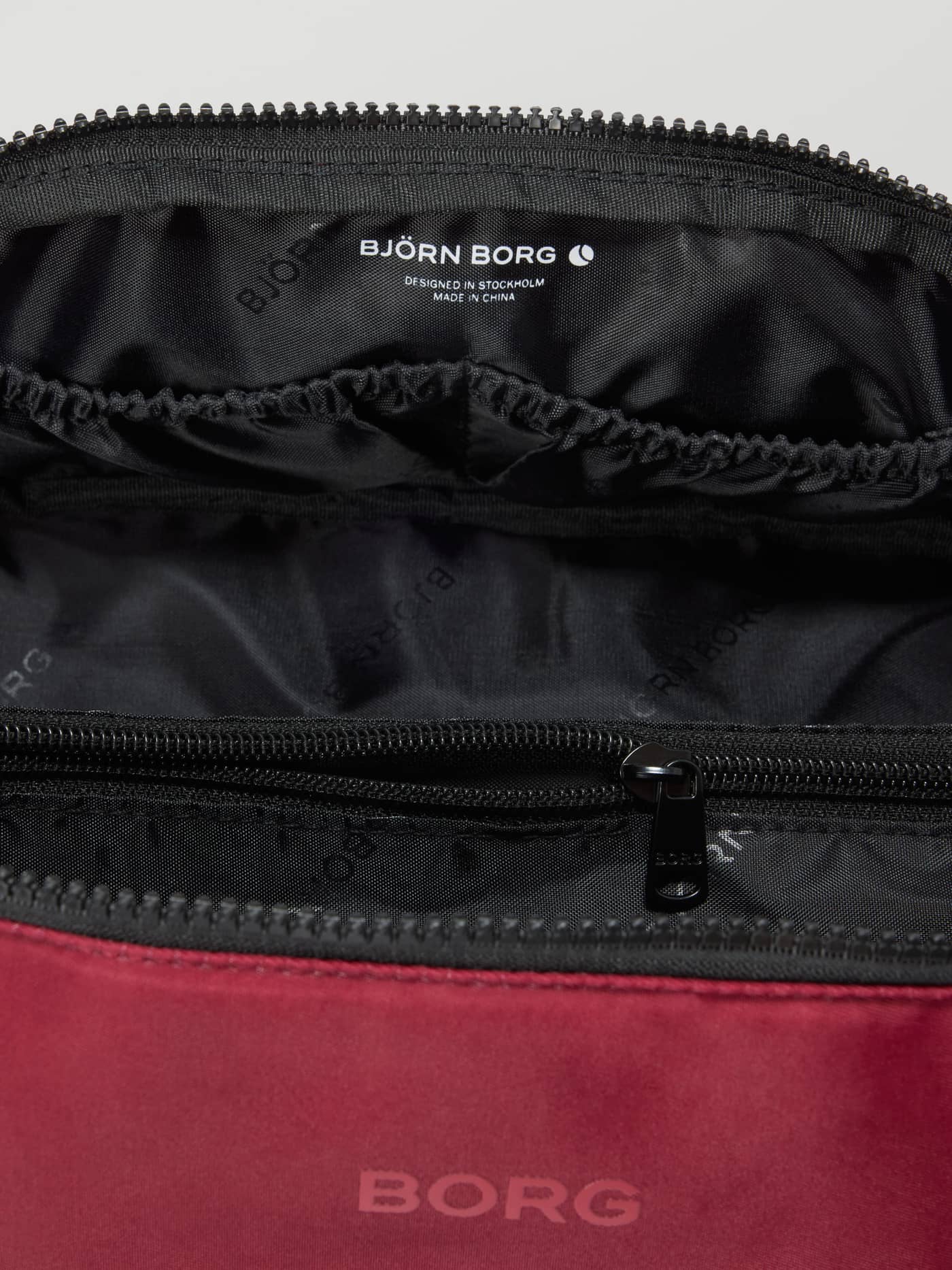 Interior view of the Borg Classic Wash Bag in Cabernet (Red) with inside pockets and white logo for training. - Image 3