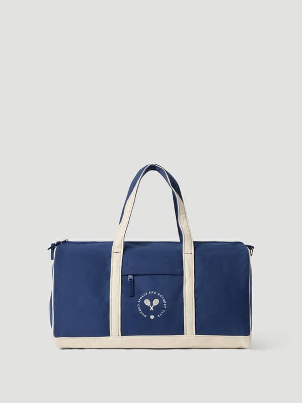 Ace Canvas Sports Bag 40L en Blue Depths (Bleu) en toile de coton avec sangles crème et logo de tennis blanc.