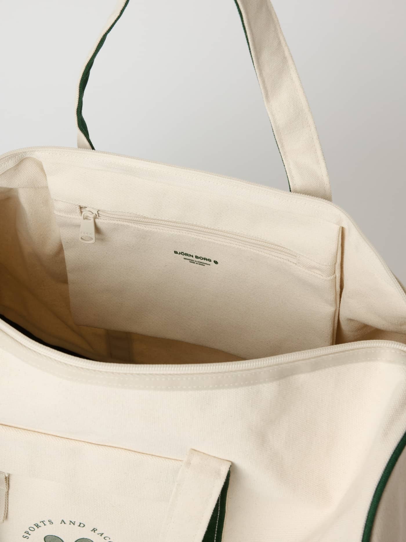 Innenansicht der Ace Canvas Sports Bag 40L in Egret (Weiß) mit schwarzem Logo auf dem Reißverschlussfach für Tennistraining. - Image 6