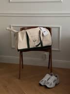 Ace Canvas Sports Bag 40L in Egret (White) made of cotton canvas with a green logo, styled for tennis performance on a chair.