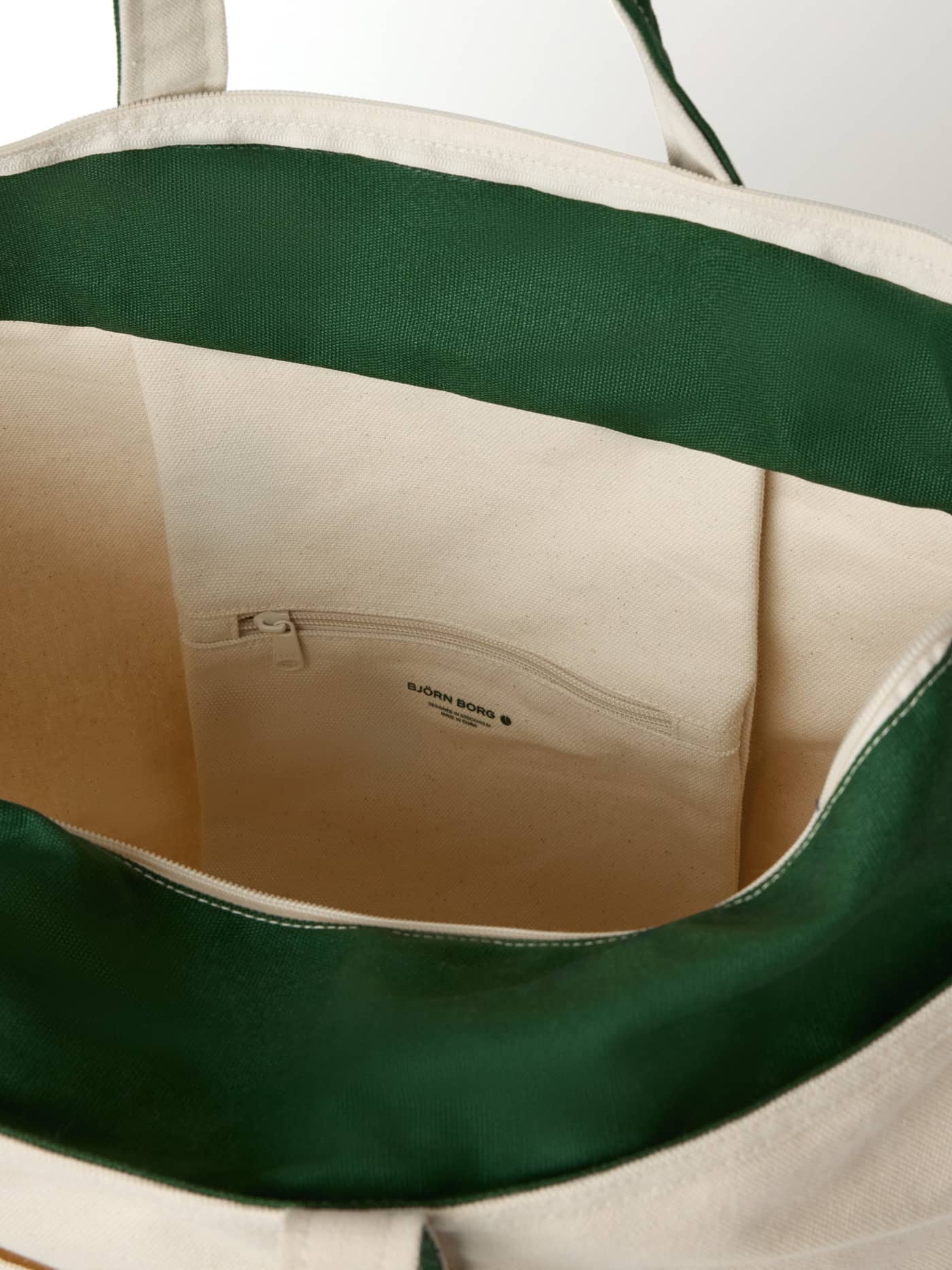 Interiøret i Ace Canvas Tote 30L i Egret (Hvit) med grønt fôr, svart logo og glidelåslomme i bomull til tennis. - Image 6