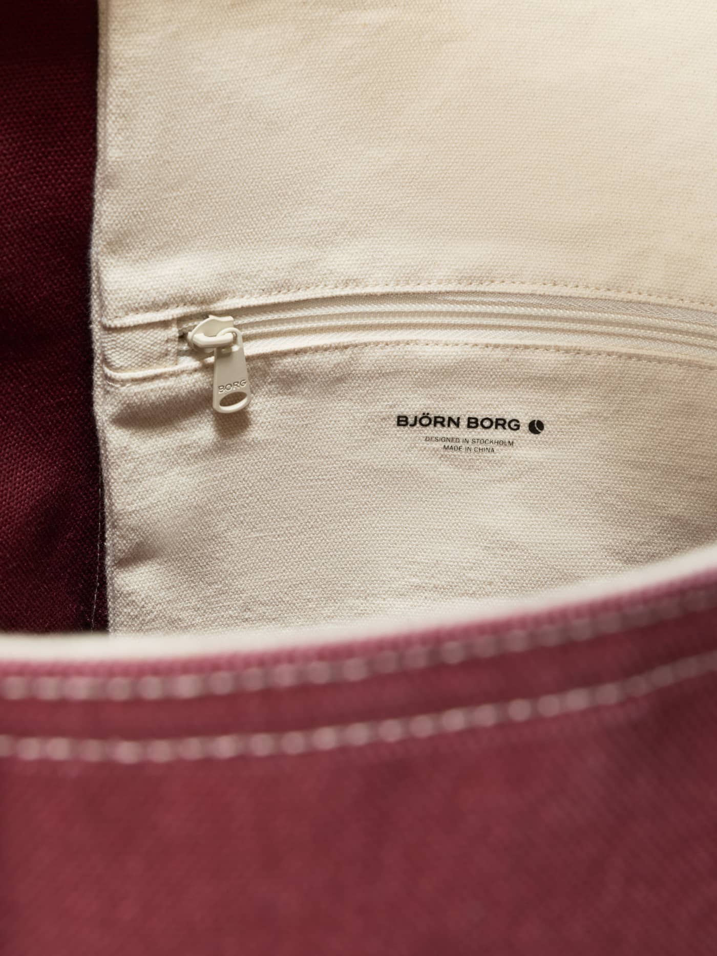 Close-up of the Cabernet (Red) Ace Canvas Tote 27L interior, showing the cotton canvas pocket and black logo for tennis. - Image 4