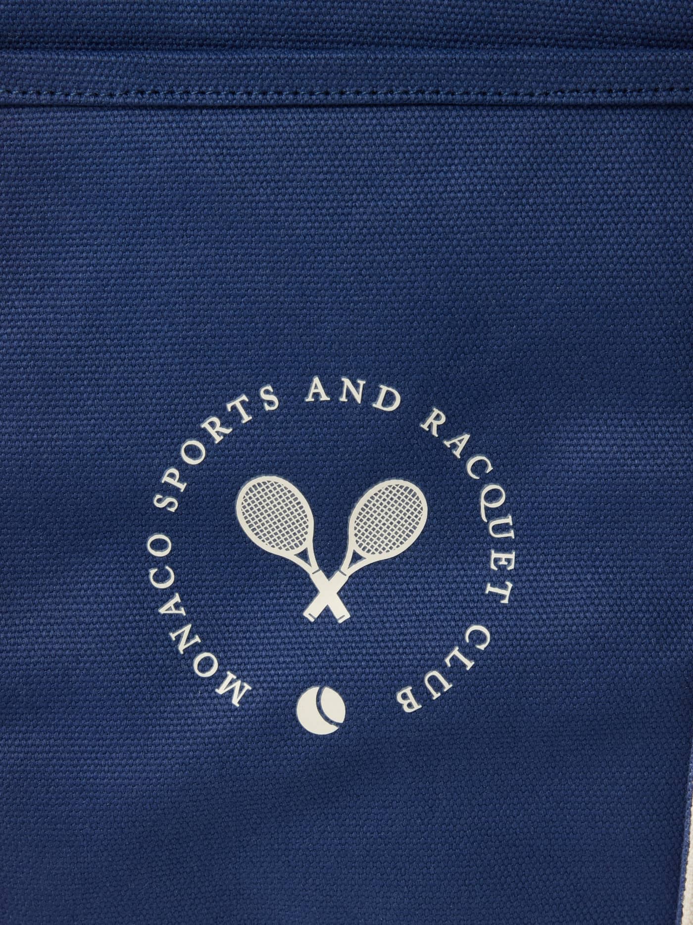 Close-up van de katoenen Björn Borg Ace Canvas Tote 30L in Blue Depths (Blauw) met een off-white tennisclublogo. - Image 4