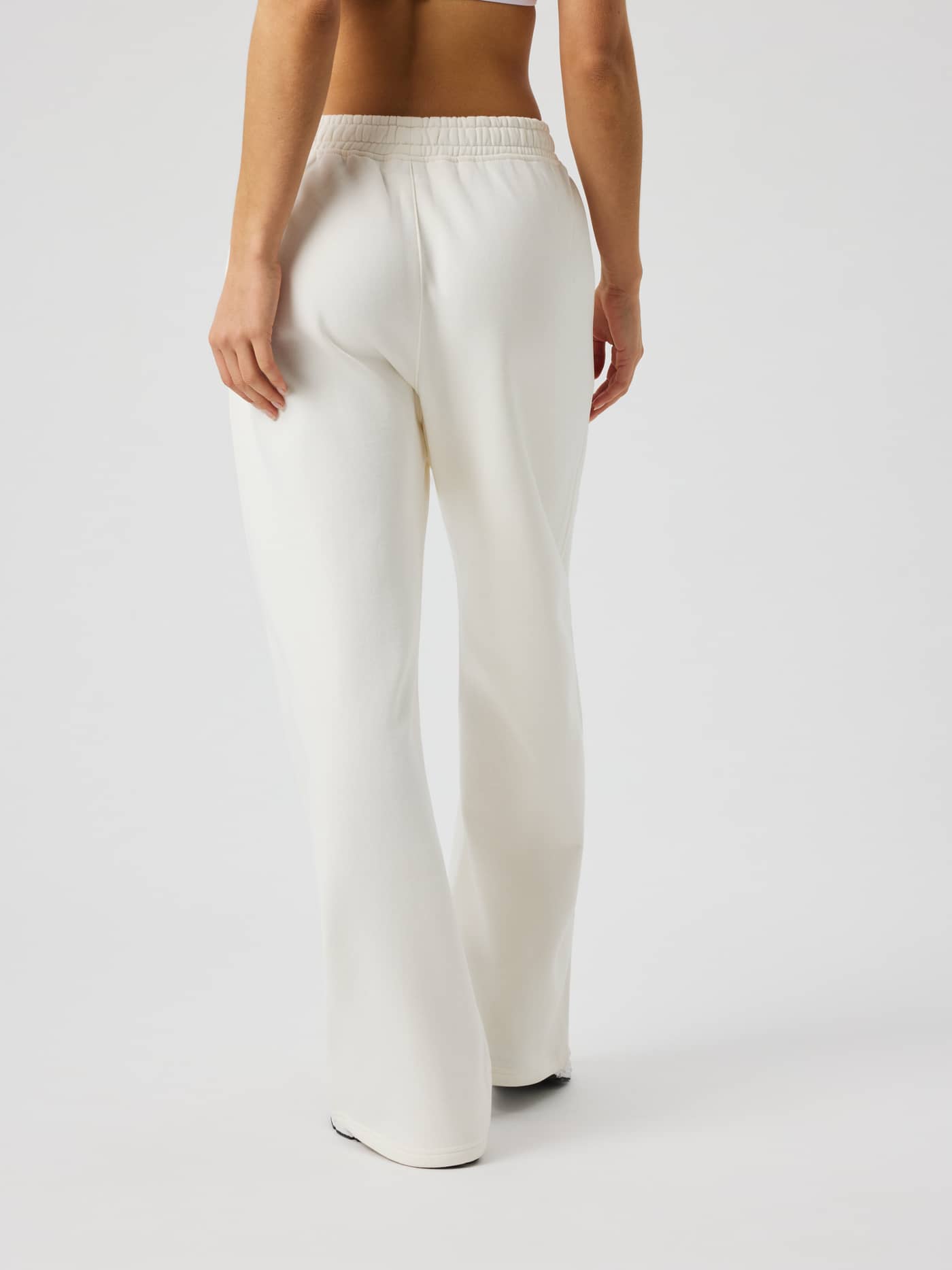 Back view of a model wearing Studio Oversized Straight Sweatpants in Tofu (White) with a relaxed fit and tennis details. - Image 3